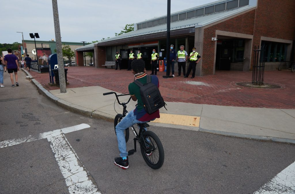 photograph of a young boy on a BMX bike photographing the police outside an MBTA station in Boston