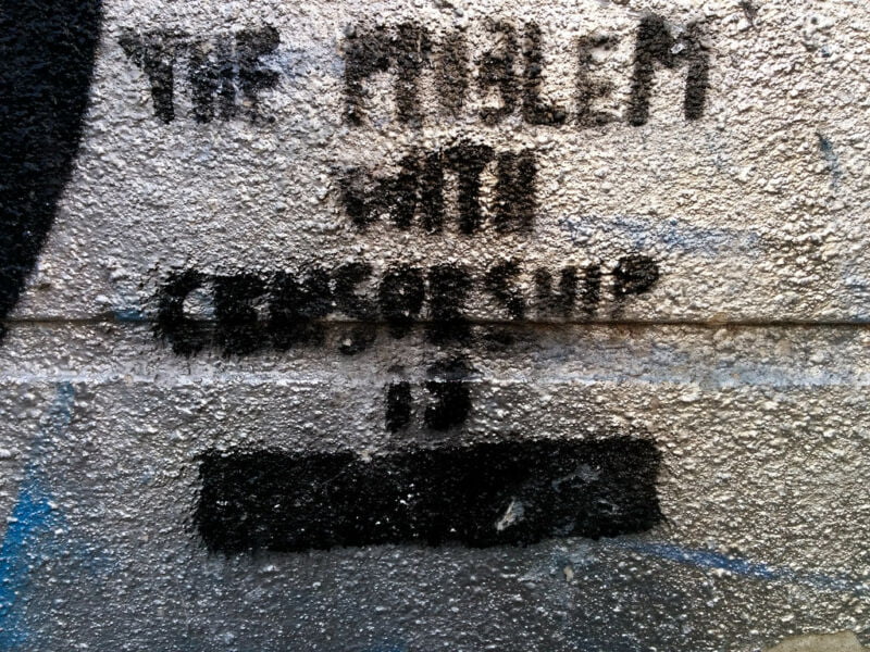 A pithy phrase regarding censorship has been spray painted on a wall: the problem with censorship is redacted.